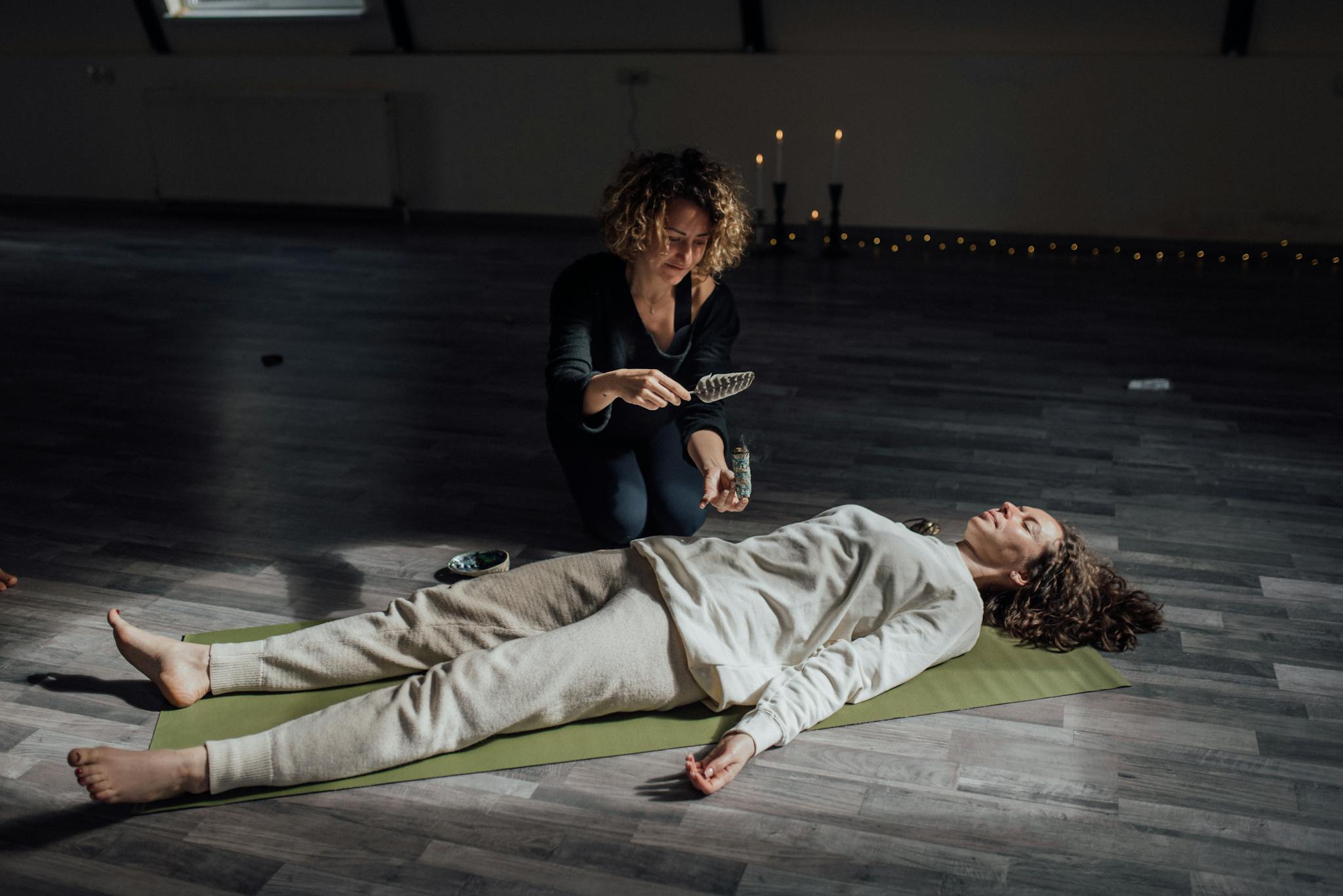 Two women engaged in alternative healing session indoors, promoting relaxation and wellness.